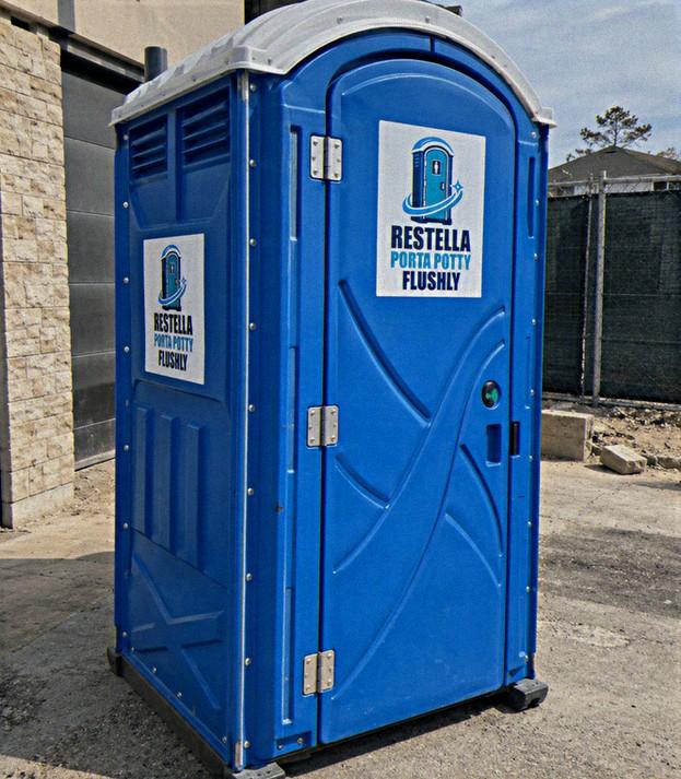 Blue standard portable restroom unit positioned at the edge of a construction site